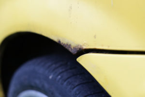 yellow car with a rust patch