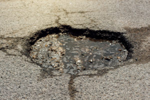 Asphalt road hole damage, close up of damaged driveway